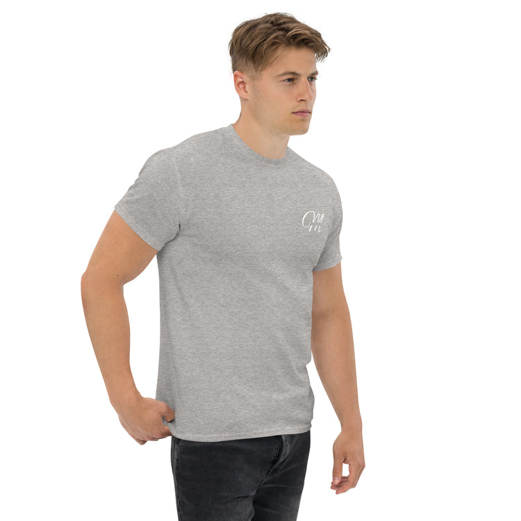 Camiseta MILLE Esencia Clásica de color gris sport con logo MILLE blanco en el pecho. Vista frontal ligeramente lateral de modelo con mano en el bolsillo.