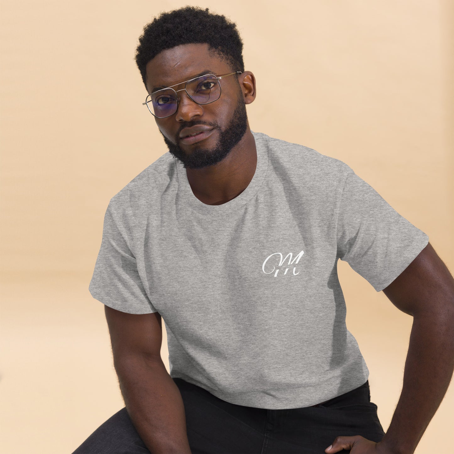 Camiseta MILLE Esencia Clásica de color gris sport con logo MILLE blanco en el pecho. Vista frontal de modelo sentado con gafas.