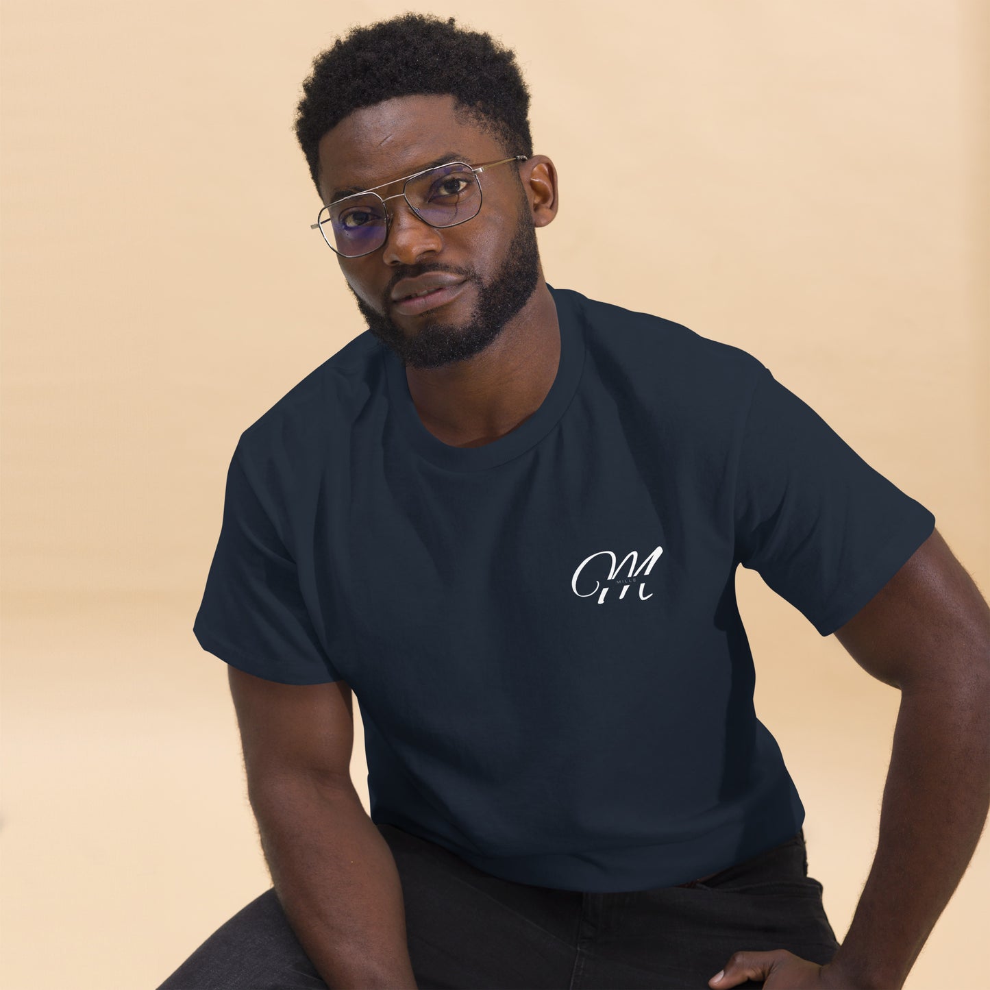 Camiseta MILLE Esencia Clásica de color marino con logo MILLE blanco en el pecho. Vista frontal de modelo sentado con gafas.