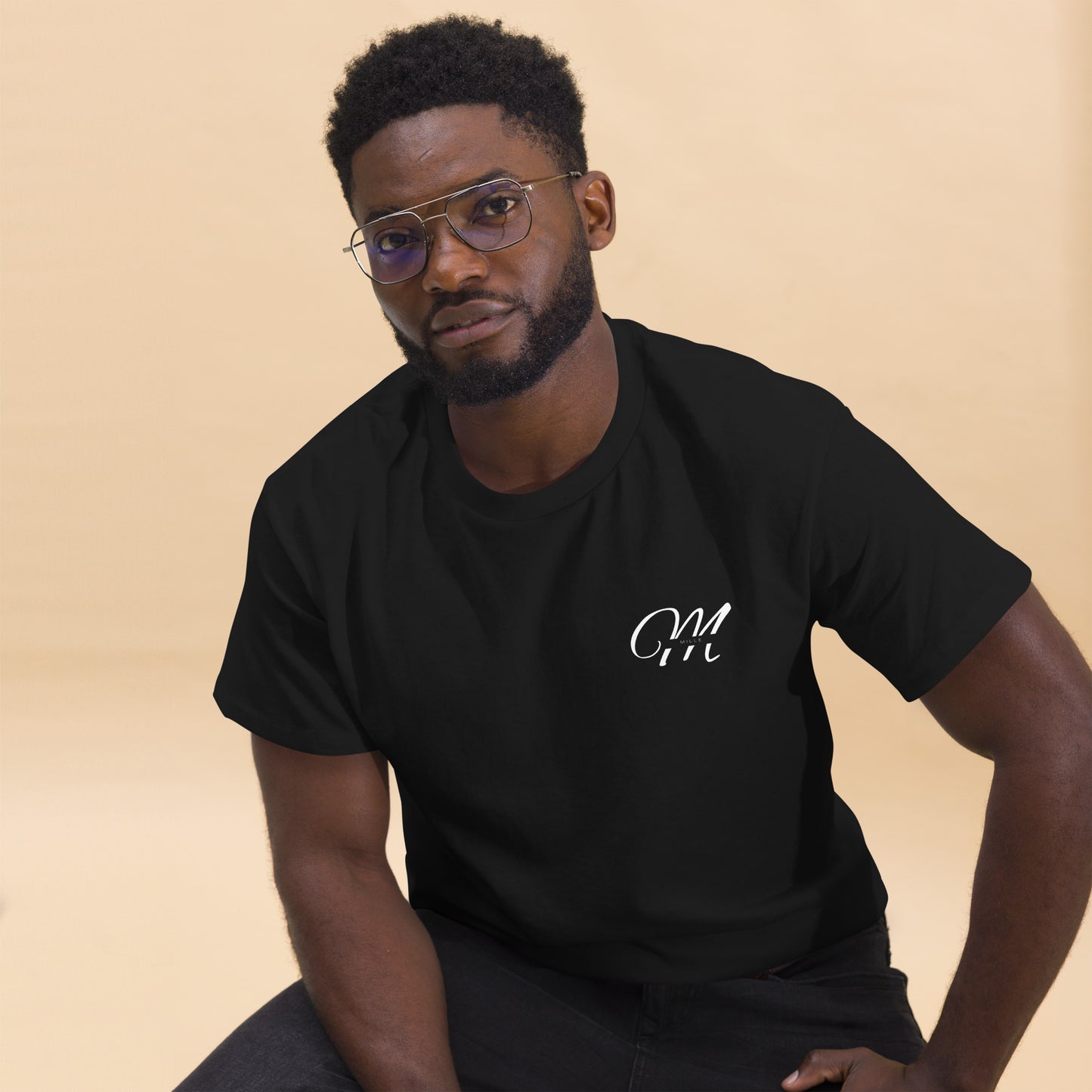 Camiseta MILLE Esencia Clásica de color negro con logo MILLE blanco en el pecho. Vista frontal de modelo sentado.