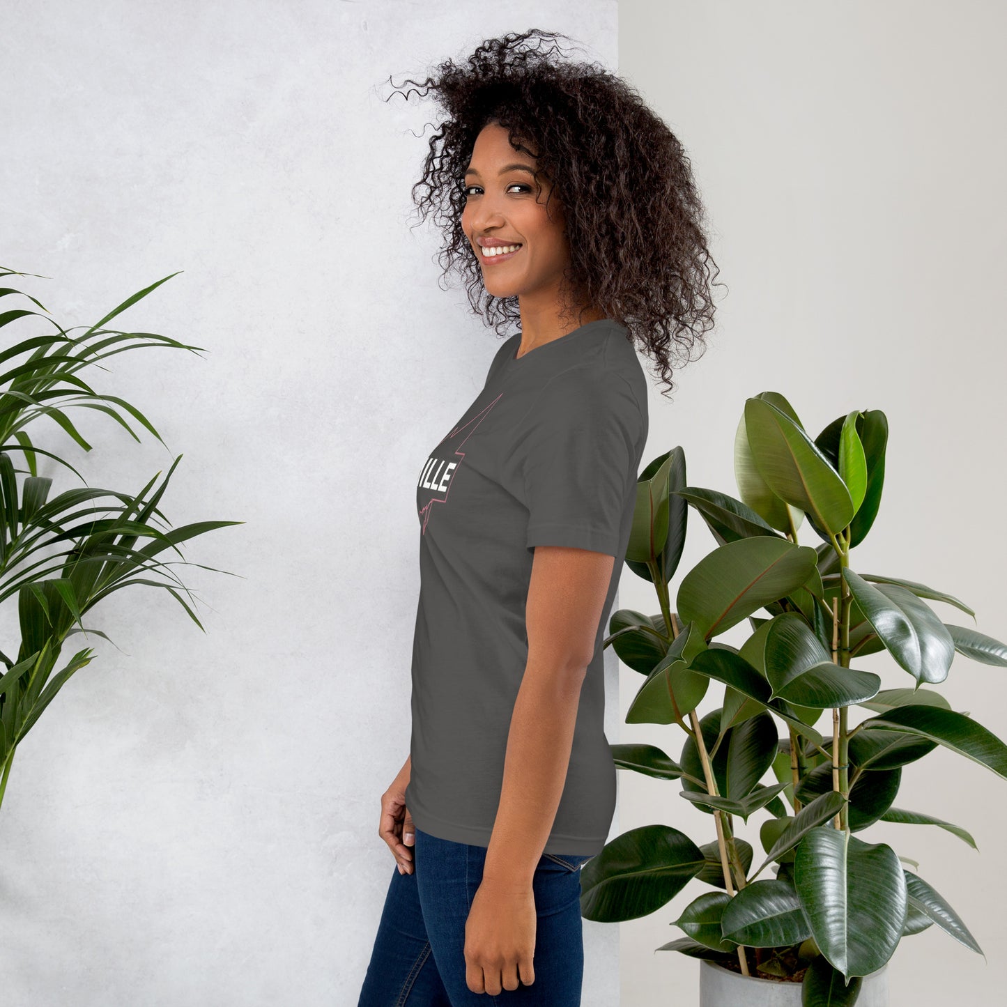Camiseta MILLE GRIT Aura de color gris carbón (Dark Grey) con logo MILLE y líneas gráficas. Vista de perfil en modelo sonriendo.