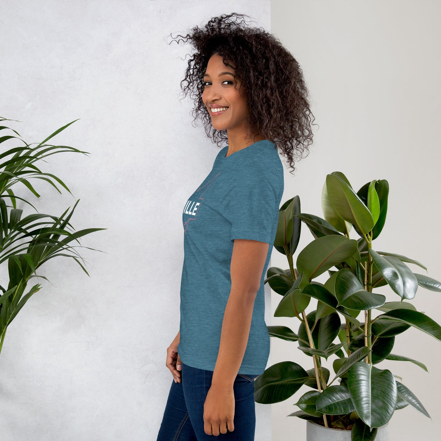 Camiseta MILLE GRIT Aura de color azul jaspeado oscuro (Heather Deep) con logo MILLE y líneas gráficas. Vista de perfil en modelo sonriendo.