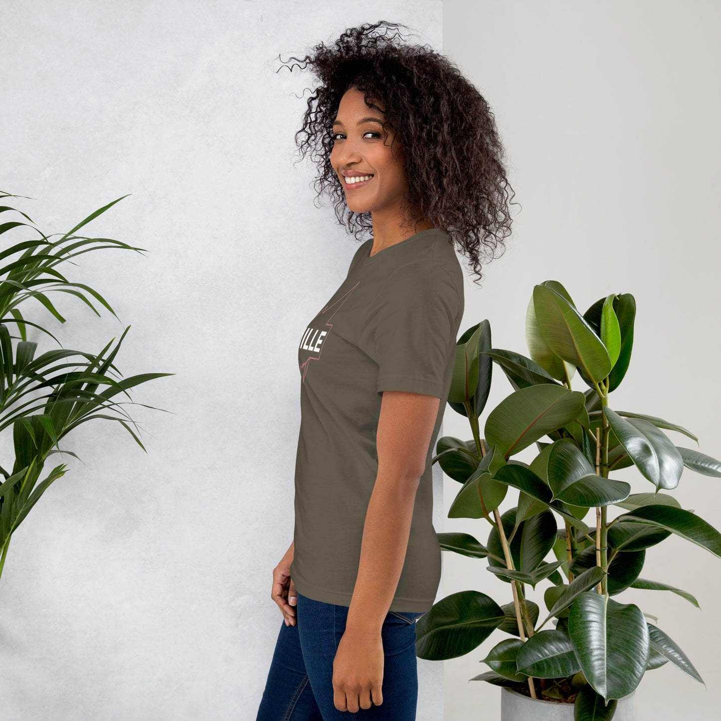 Camiseta MILLE GRIT Aura de color verde oliva (Army) con logo MILLE y líneas gráficas. Vista de perfil en modelo sonriendo.