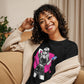 Camiseta MILLE Ink Riot de color negro con diseño de chica urbana sobre mancha de tinta fucsia. Vista frontal con modelo sonriendo en un sofá.