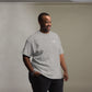 Camiseta MILLE Esencia Clásica de color gris sport con logo MILLE blanco en el pecho. Vista frontal de modelo de pie sonriendo.