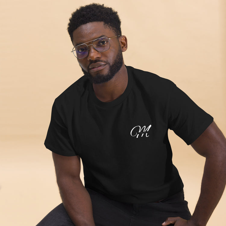 Camiseta MILLE Esencia Clásica de color negro con logo MILLE blanco en el pecho. Vista frontal de modelo sentado.