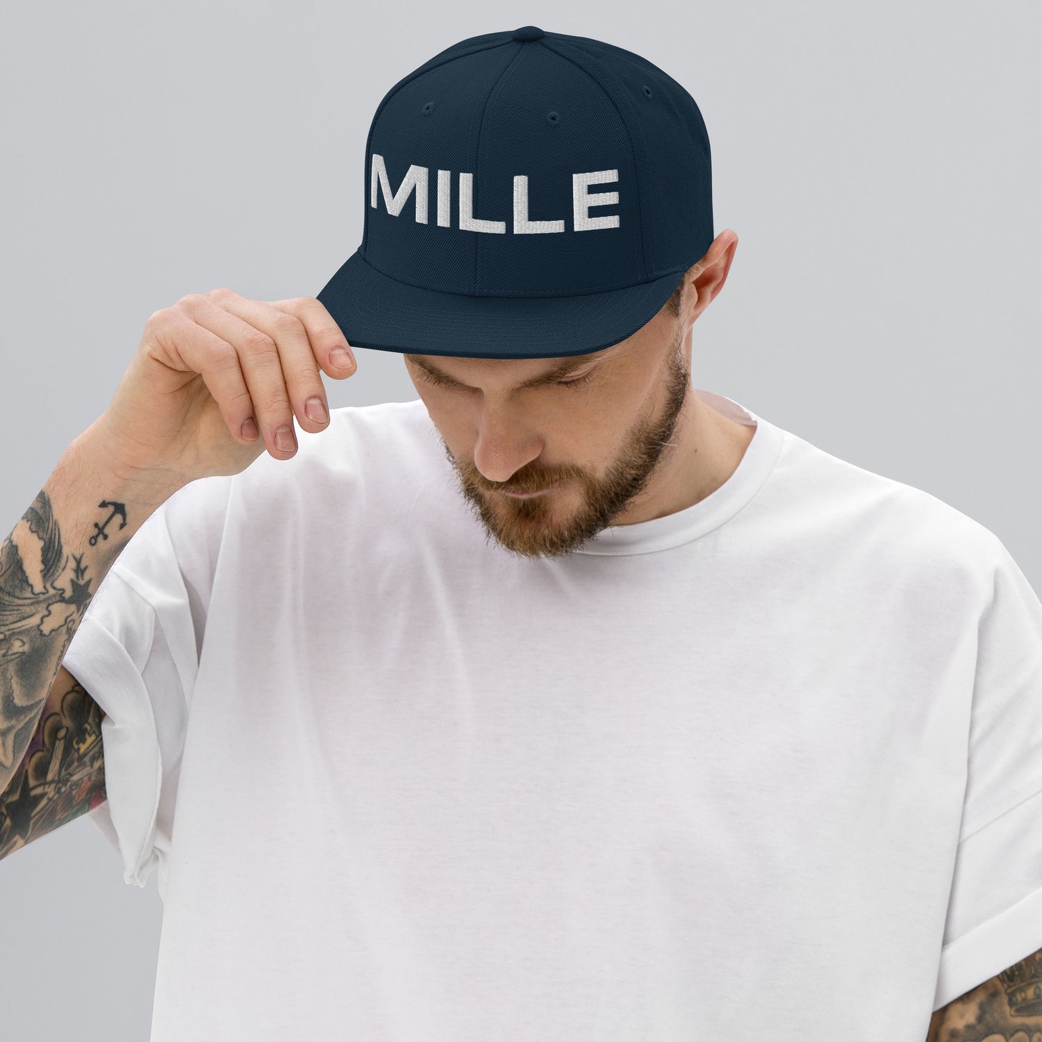 Gorra Snapback MILLE INSIGNIA de color azul marino oscuro con logo MILLE bordado en blanco. Vista frontal con modelo.