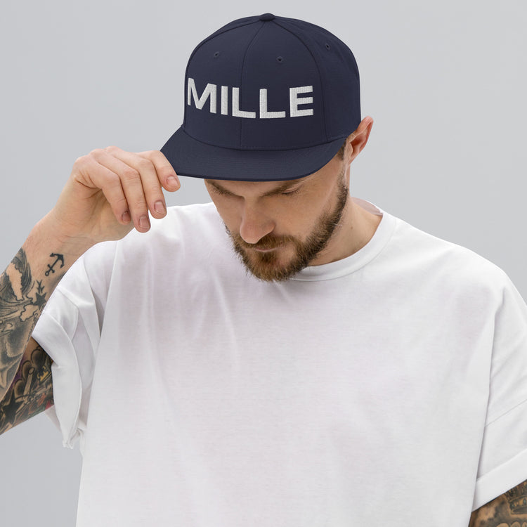 Gorra Snapback MILLE INSIGNIA de color azul marino con logo MILLE bordado en blanco. Vista frontal con modelo.