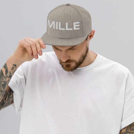 Gorra Snapback MILLE INSIGNIA de color gris jaspeado con logo MILLE bordado en blanco. Vista frontal con modelo.