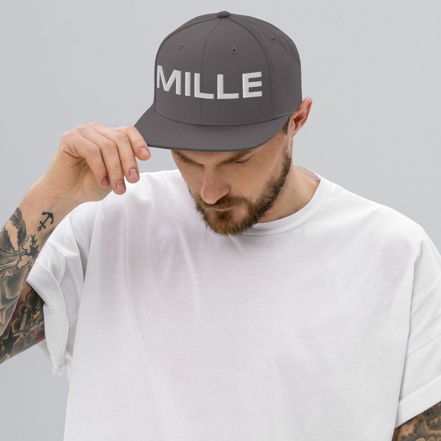 Gorra Snapback MILLE INSIGNIA de color gris oscuro con logo MILLE bordado en blanco. Vista frontal con modelo.