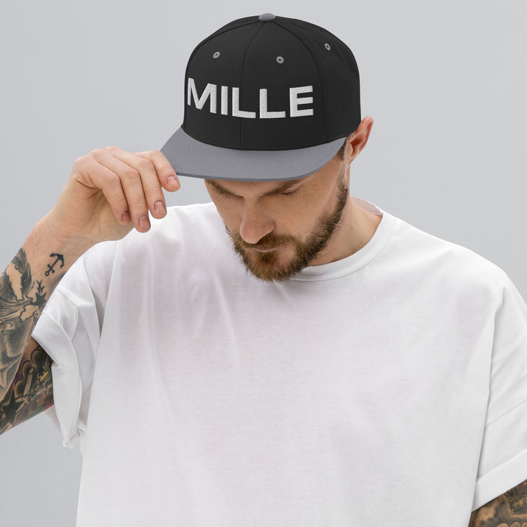 Gorra Snapback MILLE INSIGNIA de color negro con visera plateada y logo MILLE bordado en blanco. Vista frontal con modelo.