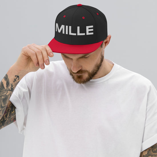 Gorra Snapback MILLE INSIGNIA de color negro con visera roja y logo MILLE bordado en blanco. Vista frontal con modelo.