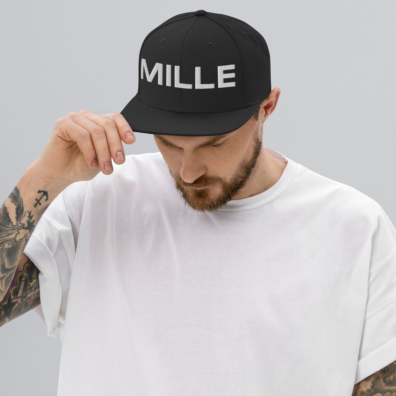 Gorra Snapback MILLE INSIGNIA de color negro con logo MILLE bordado en blanco. Vista frontal con modelo.