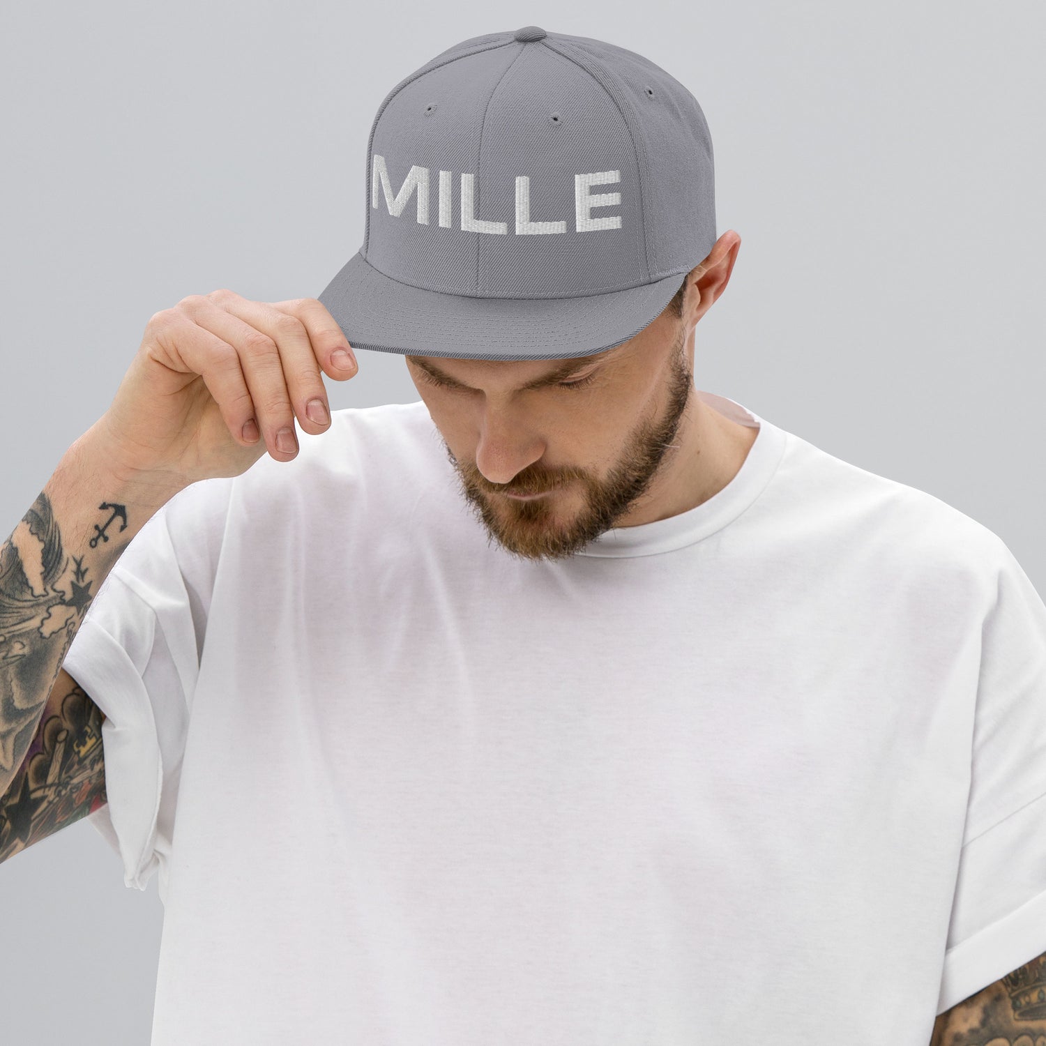 Gorra Snapback MILLE INSIGNIA de color plateado con logo MILLE bordado en blanco. Vista frontal con modelo.
