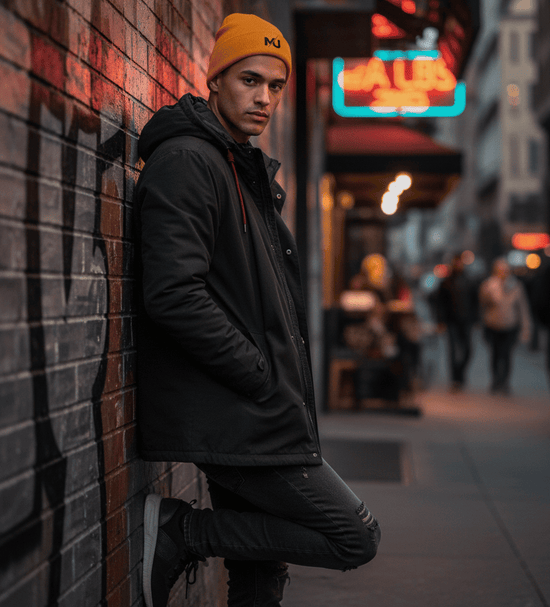 Gorro de punto MILLE DOCKER de color mostaza con logo. Vista de cuerpo completo de un modelo vistiéndolo en una calle urbana por la noche.
